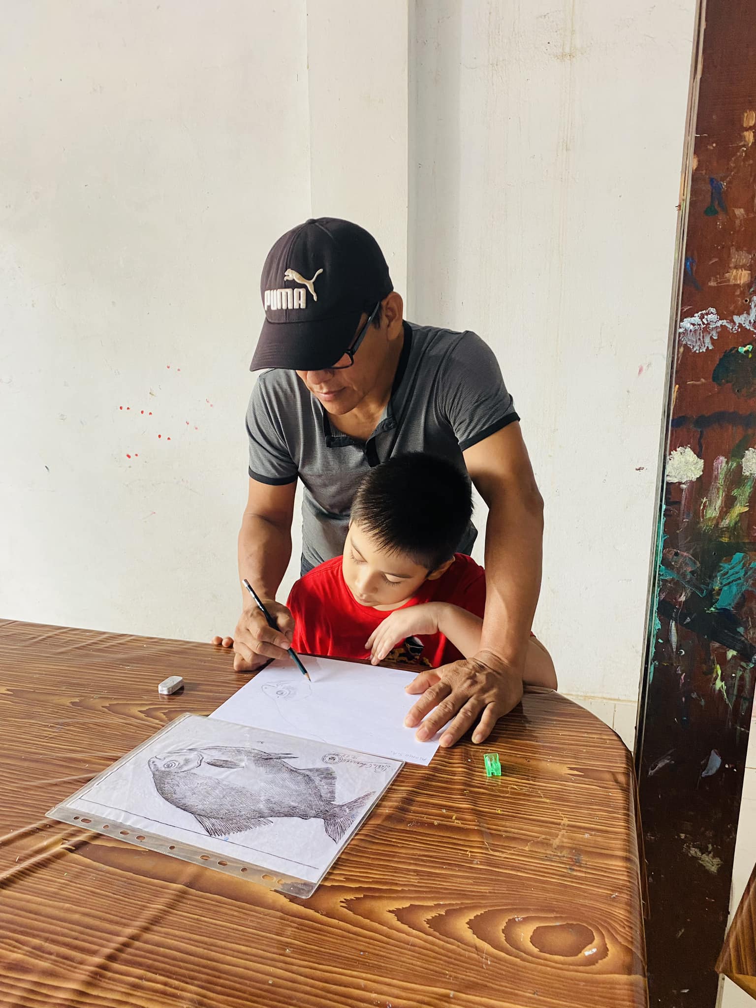 David Amaringo helping a child hold a pencil while drawing